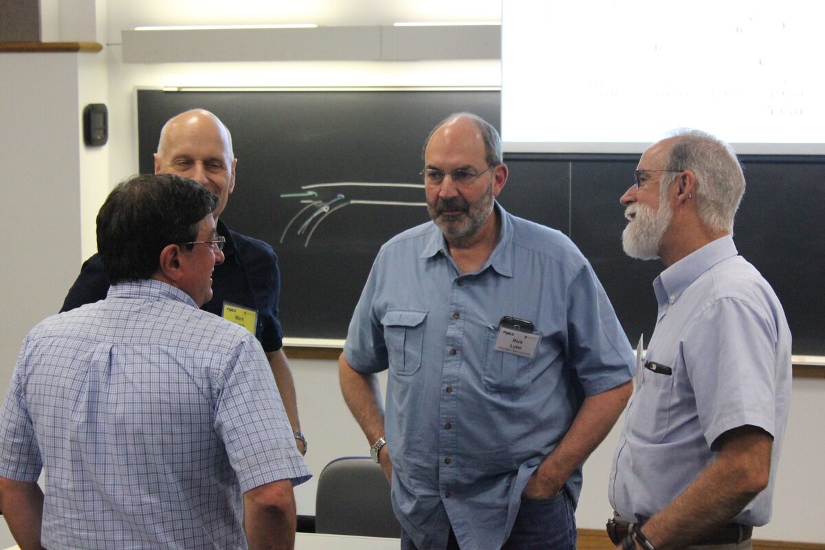 Four attendees in conversation in front of a blackboard